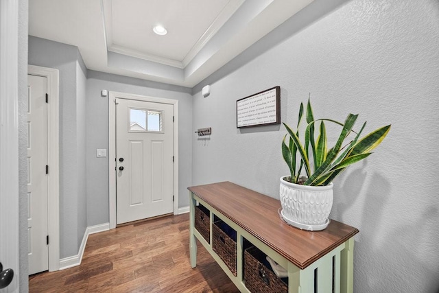 entryway featuring hardwood / wood-style flooring, a tray ceiling, and crown molding