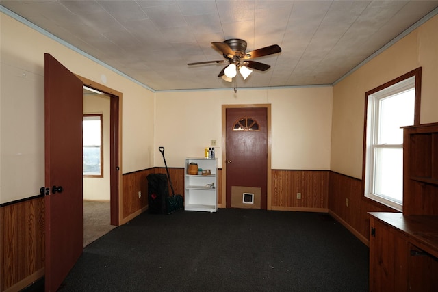 carpeted empty room featuring ceiling fan and wood walls