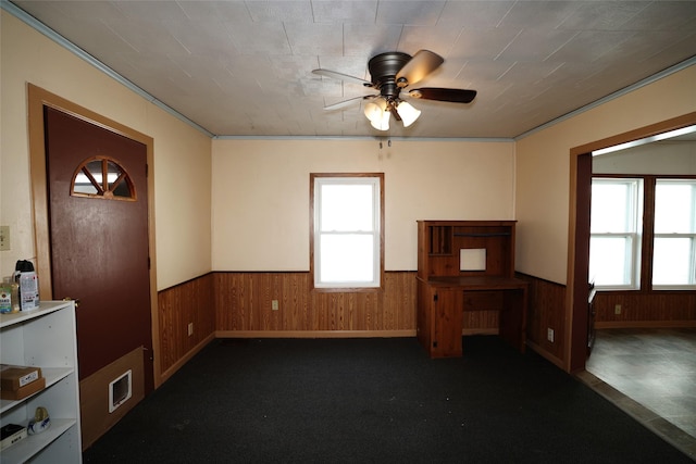 interior space featuring ceiling fan and wooden walls