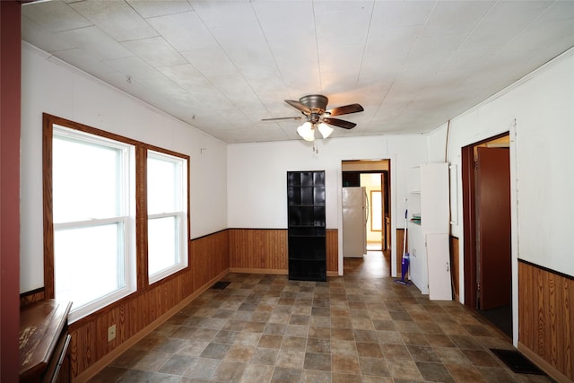 spare room featuring ceiling fan and wood walls