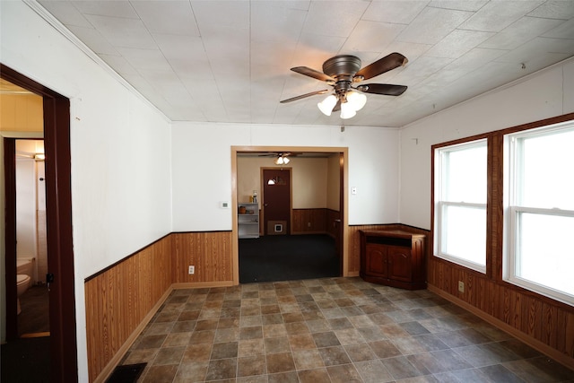 unfurnished room featuring ceiling fan and wooden walls