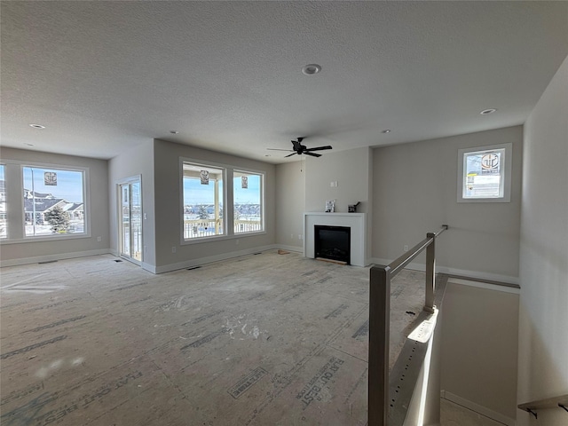 unfurnished living room featuring plenty of natural light, a fireplace, baseboards, and a textured ceiling