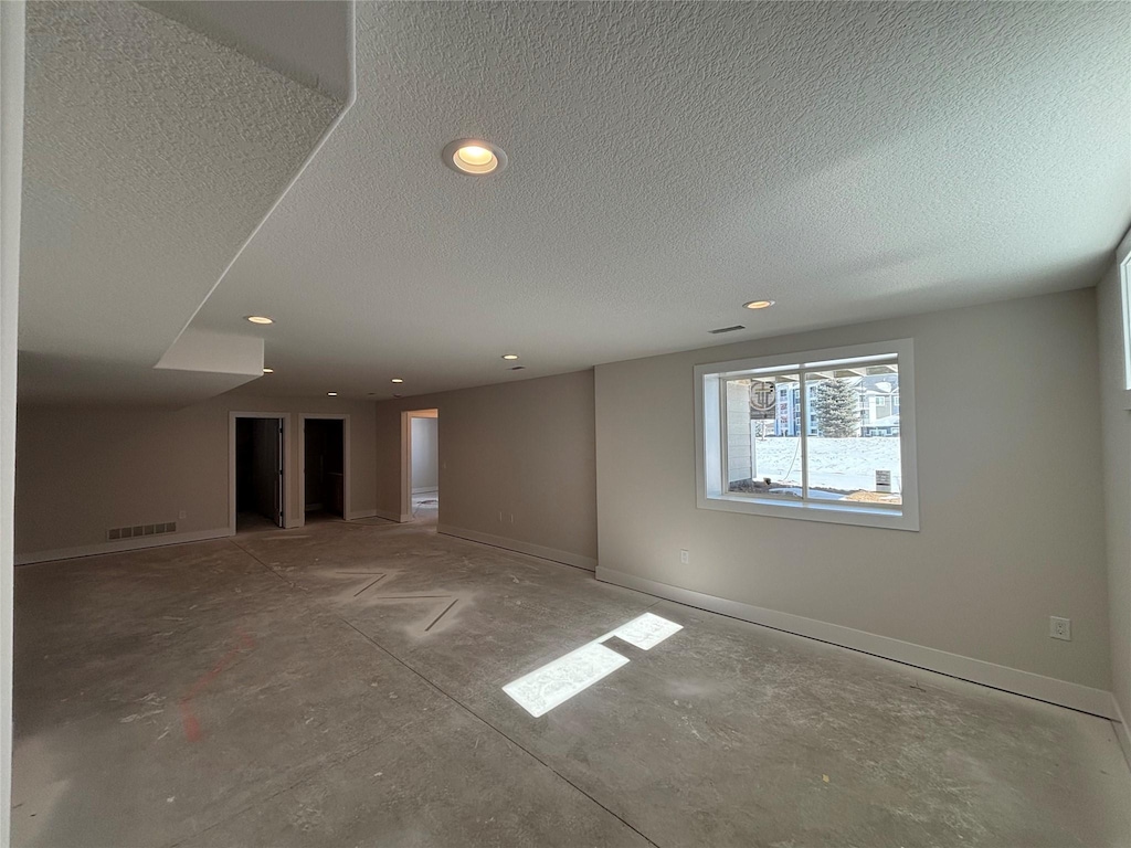 empty room featuring a textured ceiling, recessed lighting, visible vents, and baseboards