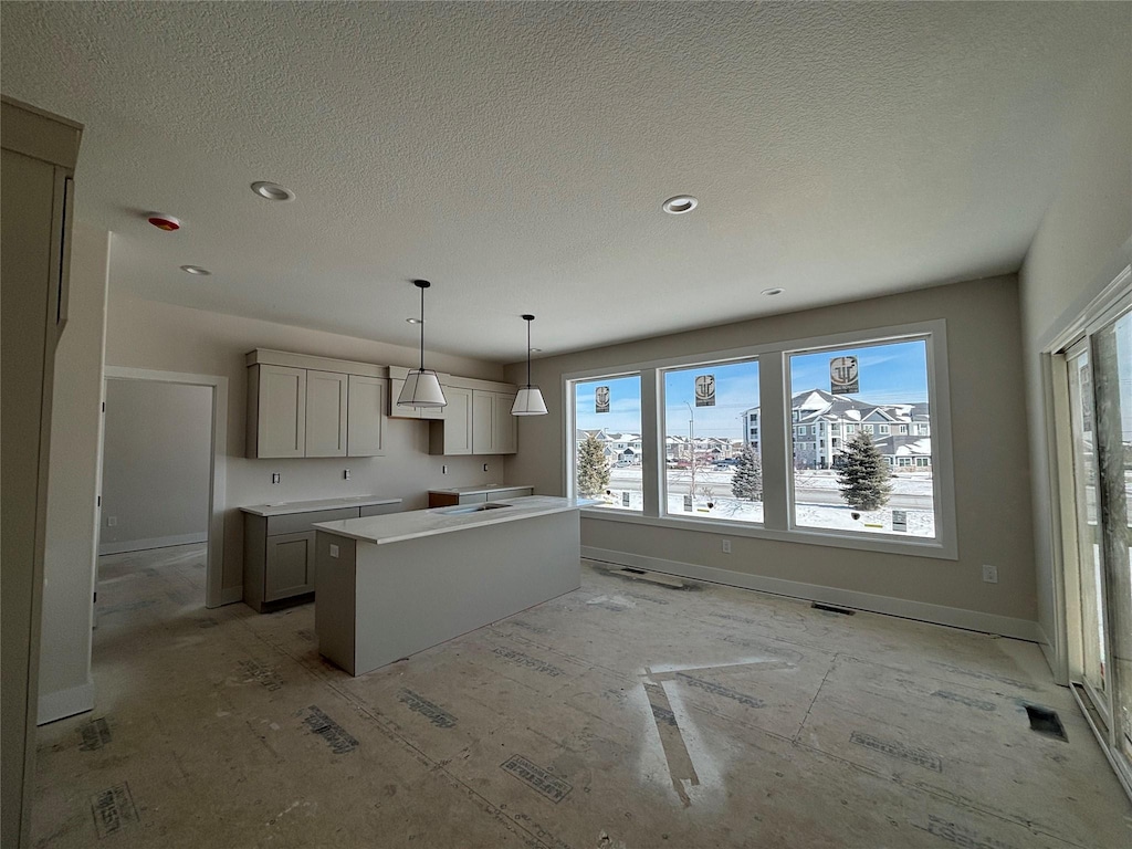 kitchen with baseboards, a center island, hanging light fixtures, light countertops, and gray cabinetry