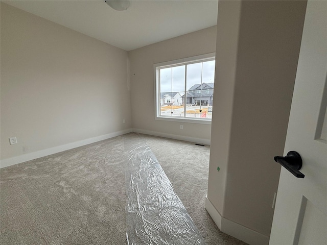 carpeted spare room featuring visible vents and baseboards