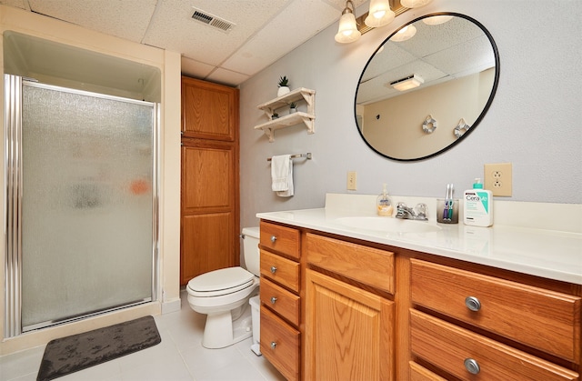 bathroom featuring a paneled ceiling, vanity, an enclosed shower, tile patterned floors, and toilet