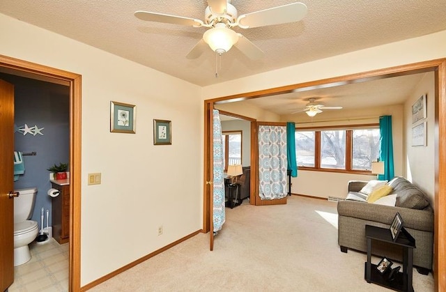 interior space with ceiling fan, light colored carpet, and a textured ceiling