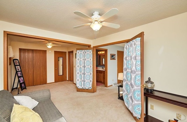 living room with ceiling fan, light colored carpet, and a textured ceiling