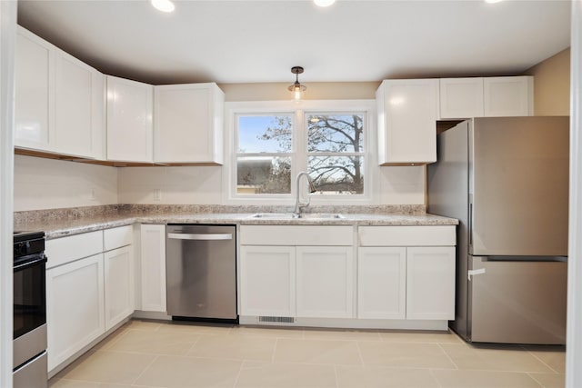 kitchen with sink, light tile patterned floors, white cabinets, and appliances with stainless steel finishes