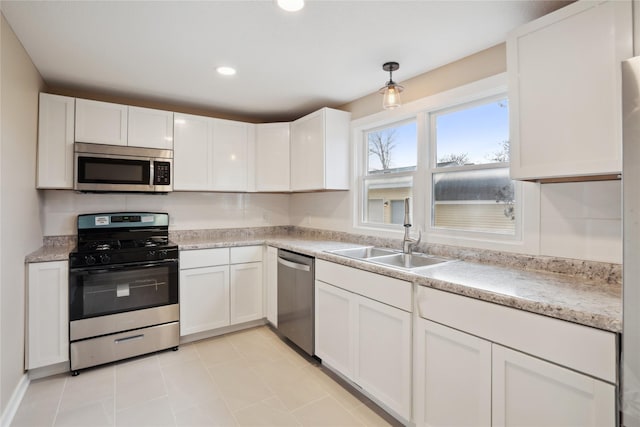 kitchen with light tile patterned flooring, sink, white cabinetry, hanging light fixtures, and stainless steel appliances