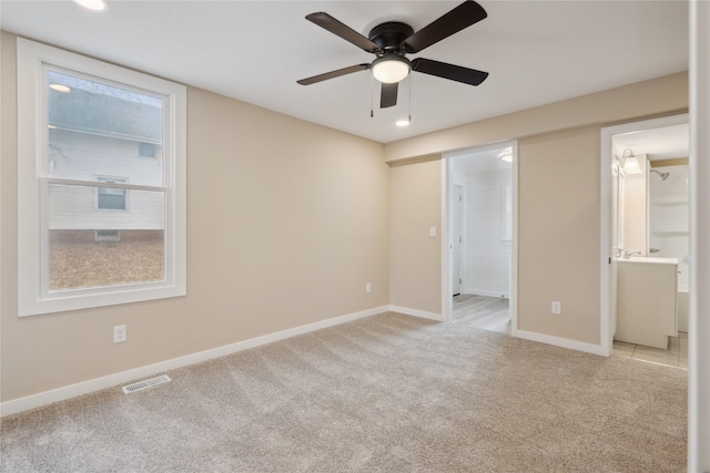 unfurnished bedroom with light colored carpet, ceiling fan, and ensuite bathroom