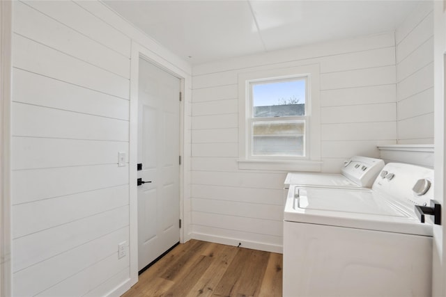 clothes washing area with washing machine and dryer and light hardwood / wood-style floors