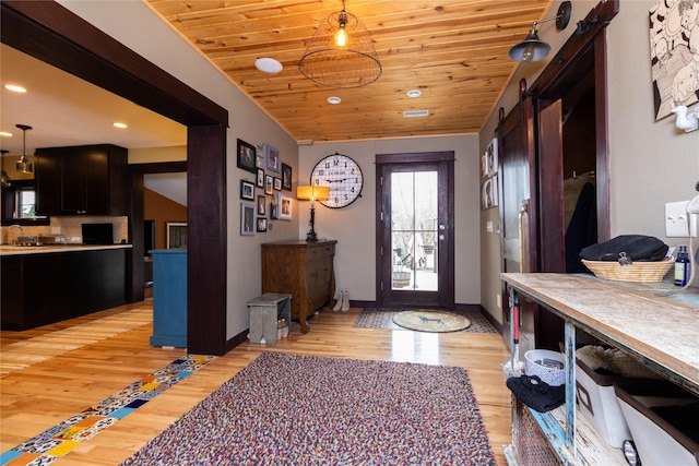 foyer featuring wooden ceiling, a barn door, vaulted ceiling, and light wood-type flooring