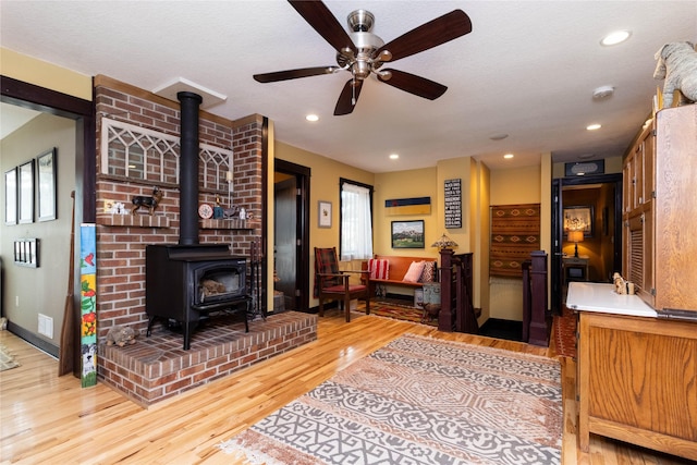 living room with ceiling fan, wood-type flooring, a textured ceiling, and a wood stove