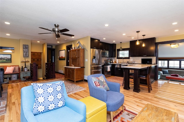 living room featuring ceiling fan and light wood-type flooring