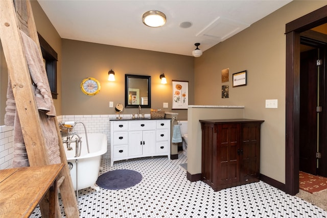 bathroom featuring vanity, a bath, tile walls, and toilet