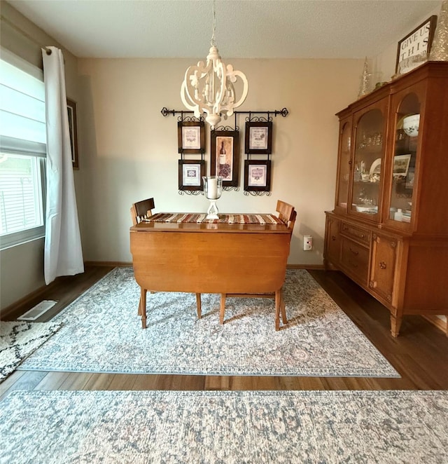 dining area featuring an inviting chandelier, dark hardwood / wood-style floors, and a textured ceiling