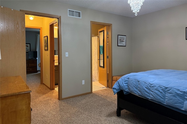 carpeted bedroom with a chandelier, a textured ceiling, and ensuite bathroom