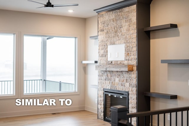 unfurnished living room featuring ceiling fan, a stone fireplace, and light hardwood / wood-style flooring