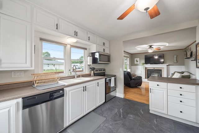 kitchen featuring appliances with stainless steel finishes, sink, white cabinets, and ceiling fan