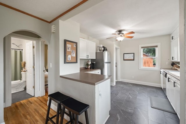 kitchen with a breakfast bar area, white cabinetry, dishwasher, kitchen peninsula, and ceiling fan