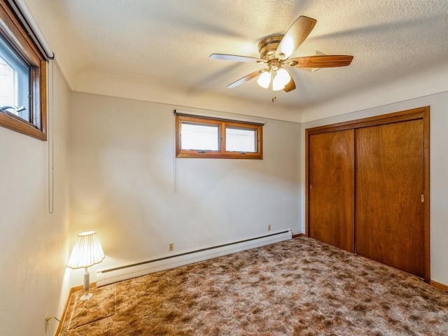 unfurnished bedroom with carpet flooring, a baseboard heating unit, ceiling fan, a textured ceiling, and a closet