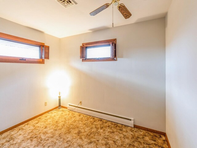 carpeted empty room featuring ceiling fan and a baseboard heating unit