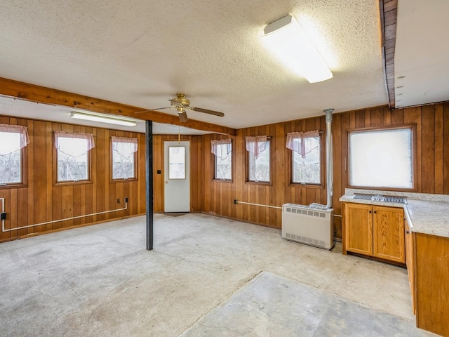 interior space featuring light colored carpet, a textured ceiling, and wood walls