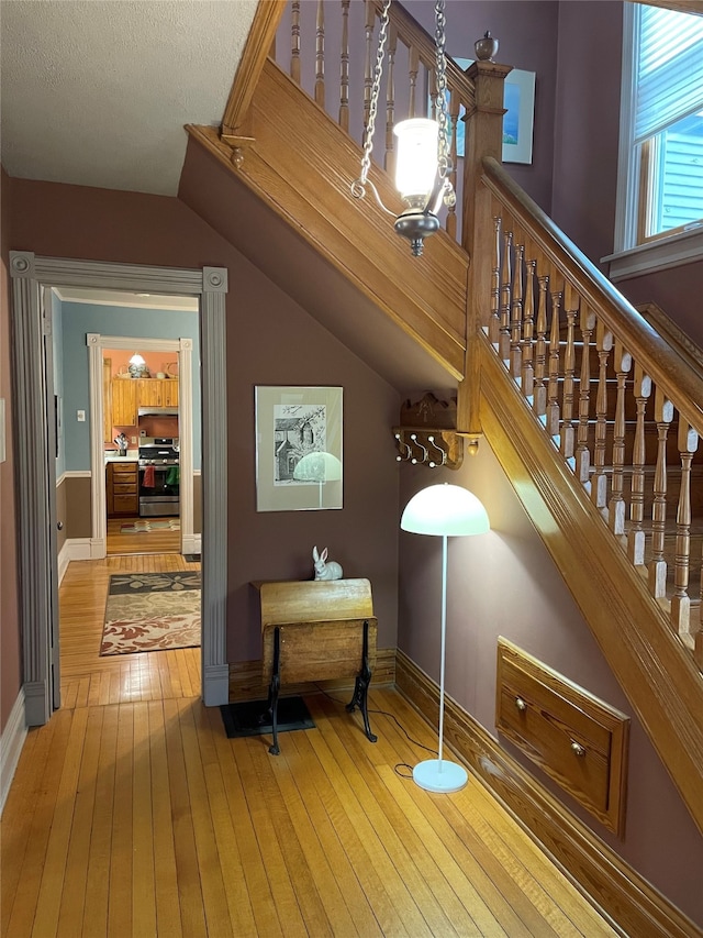 stairway with wood-type flooring and lofted ceiling