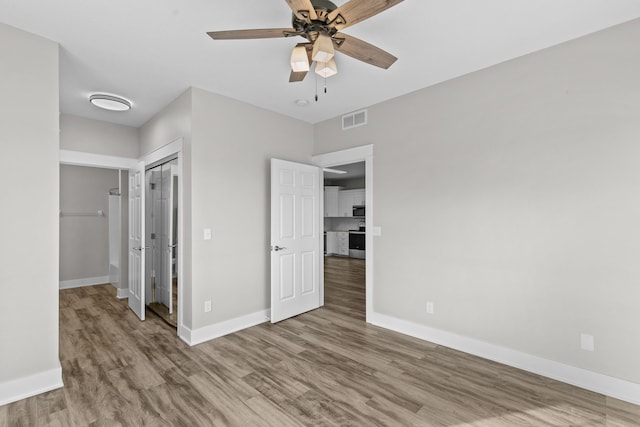 unfurnished bedroom with hardwood / wood-style flooring, ceiling fan, and a closet