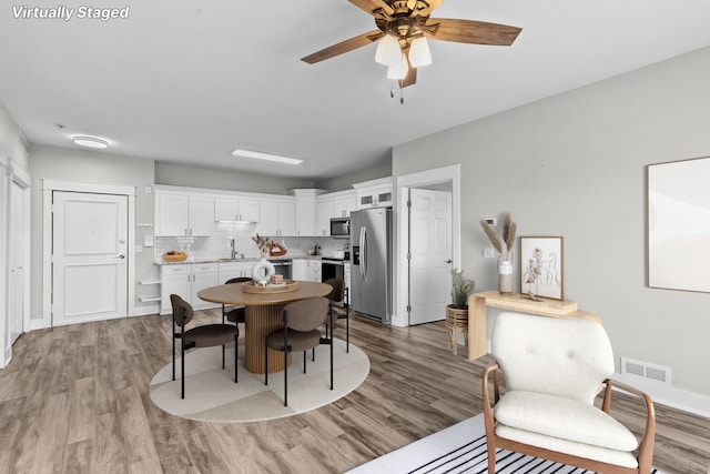 dining area featuring ceiling fan, wood-type flooring, and sink