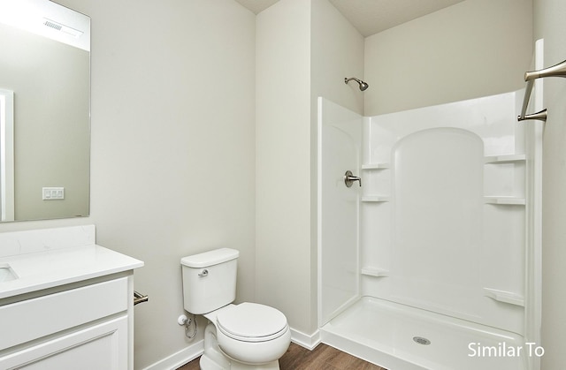 bathroom featuring walk in shower, vanity, toilet, and hardwood / wood-style floors