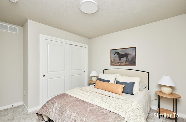 carpeted bedroom featuring a textured ceiling and a closet