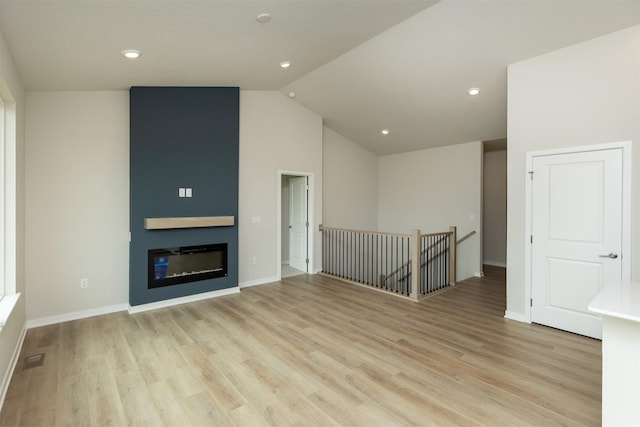 6433 NE 11th Ct, Des Moines, IA 50313 - unfurnished living room with vaulted ceiling, light wood-style floors, baseboards, a glass covered fireplace, and recessed lighting