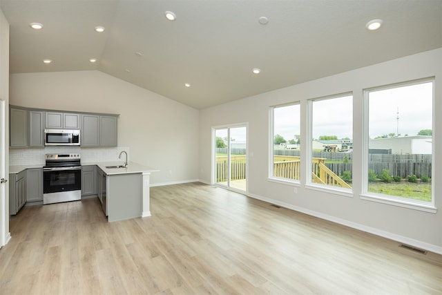 6433 NE 11th Ct, Des Moines, IA 50313 - kitchen featuring appliances with stainless steel finishes, gray cabinets, a sink, lofted ceiling, and open floor plan