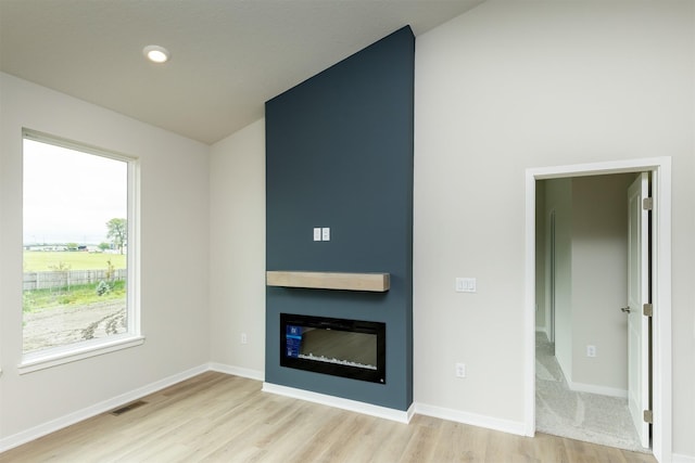 6433 NE 11th Ct, Des Moines, IA 50313 - unfurnished living room featuring light wood finished floors, a large fireplace, baseboards, vaulted ceiling, and recessed lighting