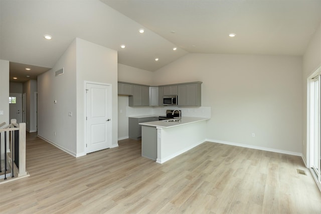 6433 NE 11th Ct, Des Moines, IA 50313 - kitchen with appliances with stainless steel finishes, gray cabinetry, a peninsula, a sink, and light countertops