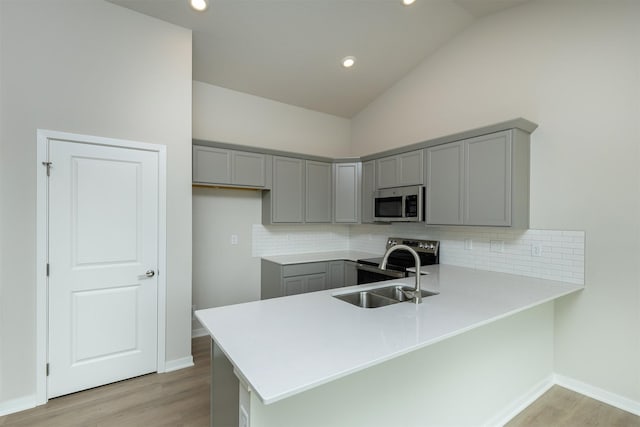 6433 NE 11th Ct, Des Moines, IA 50313 - kitchen featuring gray cabinets, stainless steel appliances, a peninsula, light wood-type flooring, and recessed lighting