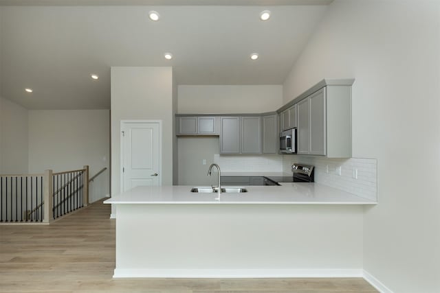 6433 NE 11th Ct, Des Moines, IA 50313 - kitchen with a sink, appliances with stainless steel finishes, gray cabinetry, a peninsula, and recessed lighting