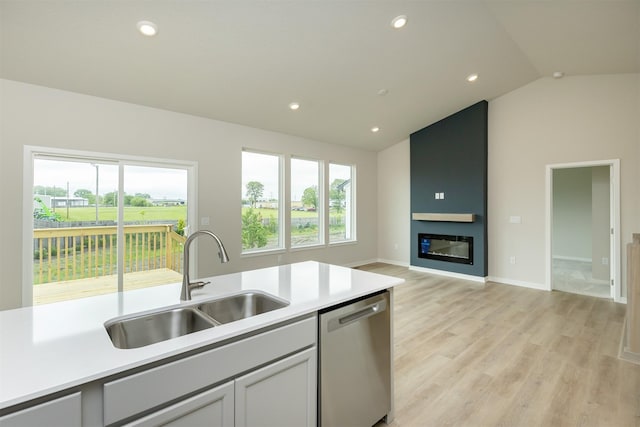 6433 NE 11th Ct, Des Moines, IA 50313 - kitchen with stainless steel dishwasher, a sink, vaulted ceiling, light countertops, and light wood-type flooring