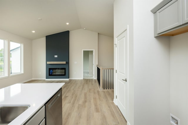 6433 NE 11th Ct, Des Moines, IA 50313 - kitchen featuring stainless steel dishwasher, light wood-type flooring, vaulted ceiling, light countertops, and recessed lighting
