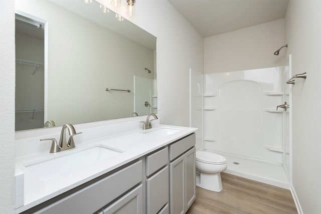 6433 NE 11th Ct, Des Moines, IA 50313 - full bathroom featuring wood finished floors, a shower, toilet, and double vanity