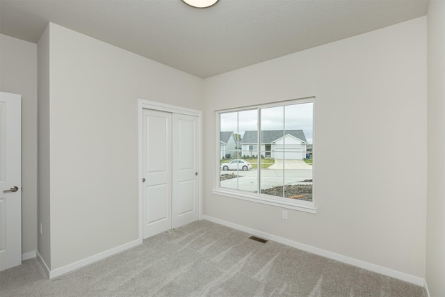 6433 NE 11th Ct, Des Moines, IA 50313 - unfurnished bedroom with light carpet, baseboards, and a closet