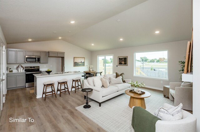 living area featuring recessed lighting, baseboards, lofted ceiling, and light wood-style floors