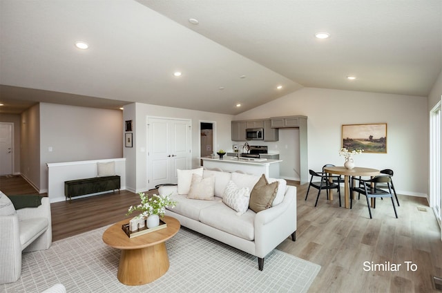 living room with recessed lighting, baseboards, light wood-style floors, and vaulted ceiling