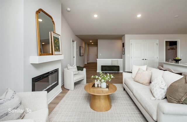 living room with a glass covered fireplace, recessed lighting, and wood finished floors