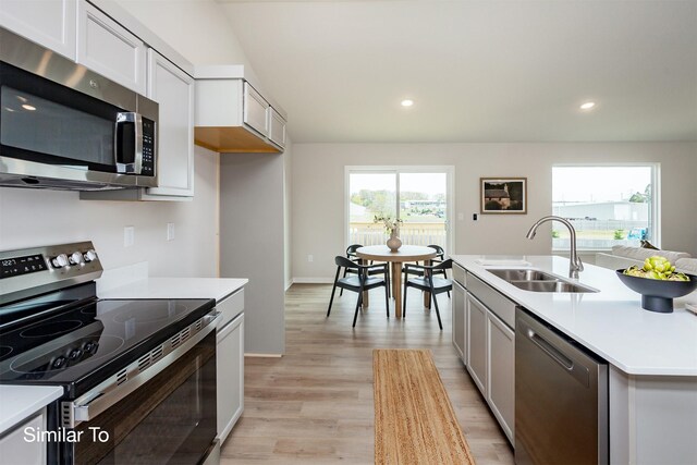 kitchen with a sink, appliances with stainless steel finishes, light wood-style flooring, and light countertops