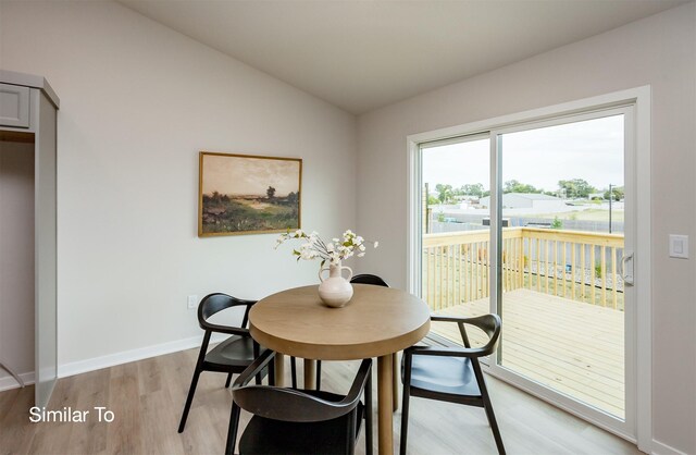 dining space with vaulted ceiling, baseboards, and light wood finished floors