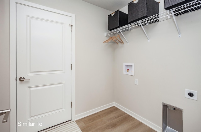 laundry area featuring electric dryer hookup, washer hookup, light wood-style floors, baseboards, and laundry area