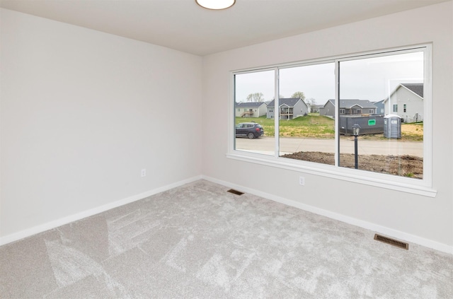 spare room featuring baseboards, carpet flooring, and visible vents
